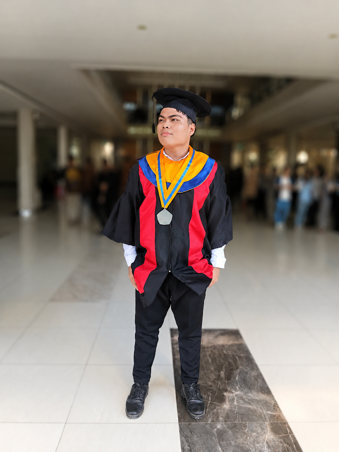 Surya Asael, S.Kom memakai toga wisuda lengkap